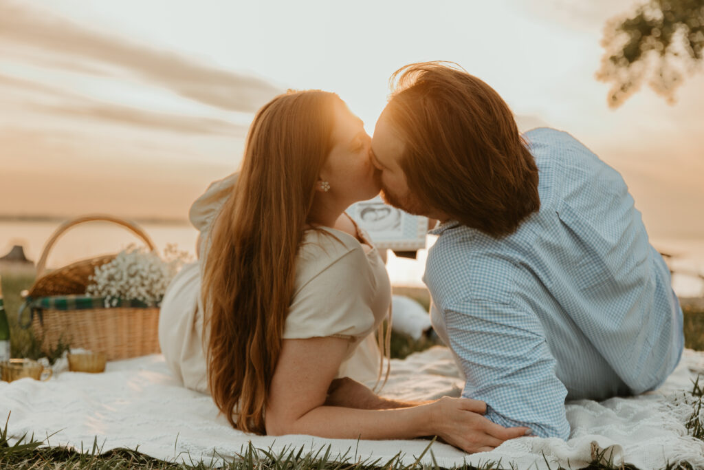 photo of couple kissing on a beach picnic at sunrise