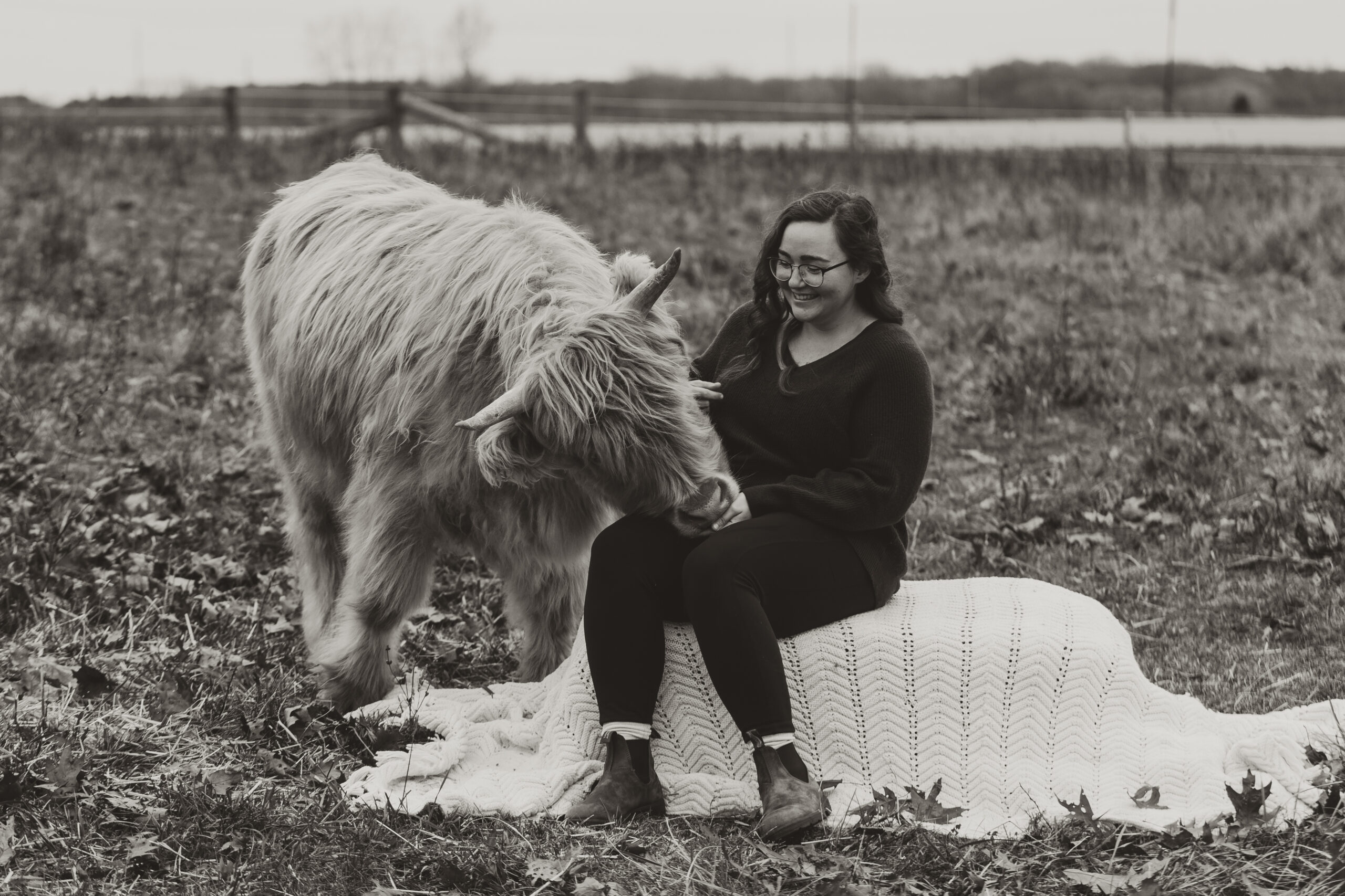 photo of photographer Callie sitting next to highland cow and smiling