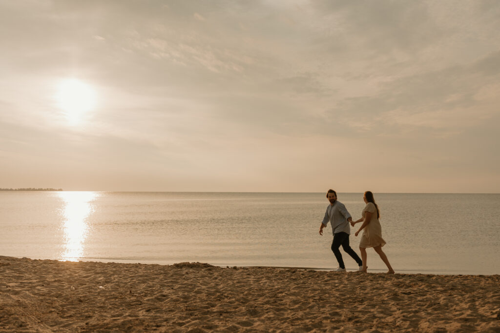 photo of couple walking on beach at sunrise